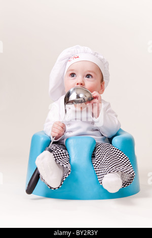 Baby-Koch mit einer Suppenkelle Cooks Outfit tragen. Stockfoto