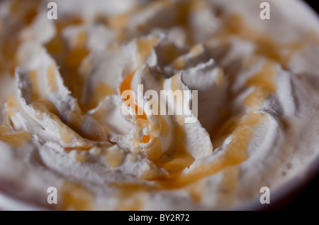 Lecker Sahne mit Karamell-Sirup und eine Kaffeetasse. Stockfoto