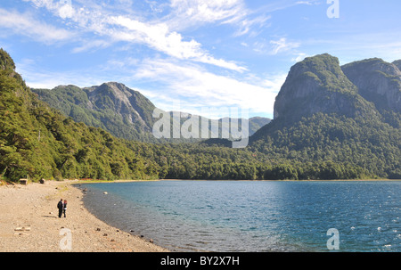 Blick auf den blauen See Brazo gesegnet, gemäßigten valdivianischen Regenwald und Granit Zinnen, mit zwei Personen an einem Strand, Anden, Argentinien Stockfoto