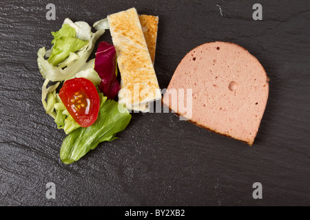 Apetiser Pastete mit Melba Toast Soldaten und kleinem Salat auf dunklem Schiefer. Stockfoto