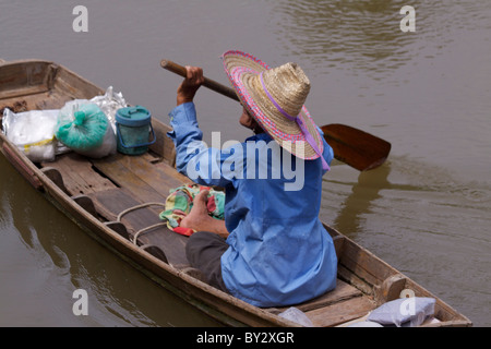 Eine alte Frau trägt einen traditionellen Strohhut Paddel entfernt in einem Holzboot aus dem Bang Noi Dorfmarkt in Samut Songkhram Stockfoto