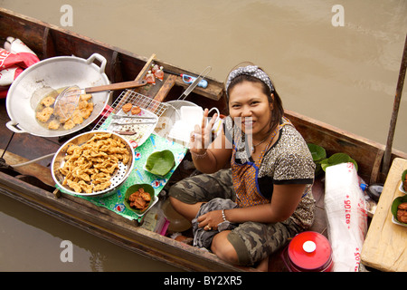 Eine Dame verkauft würzigen Krabbenküchlein gekocht auf ihren traditionellen Holzboot in Amphawa Floating Market in Samut Songkhram Stockfoto