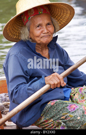 Eine alte Dame in traditionellen Hut und Kleid bringt Frucht, aus ihr Boot an der Tha Kha Floating Market in Samut Songkhram zu verkaufen Stockfoto