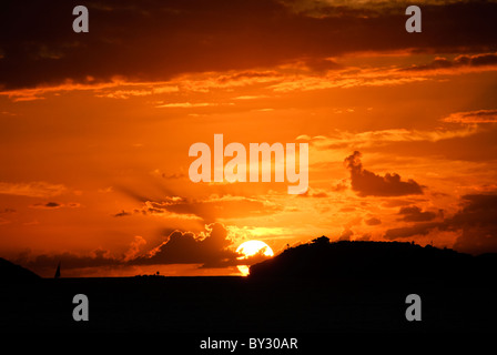 ST. JOHN, US Jungferninseln – Ein atemberaubender karibischer Sonnenuntergang von St. John auf den US Jungferninseln, während die Sonne unter dem Horizont hinter der Silhouette von St. Thomas eintaucht. Der Himmel strahlt in leuchtenden Orange-, Rosa- und Violetttönen aus, die sich von den ruhigen Gewässern der Karibik spiegeln. Stockfoto