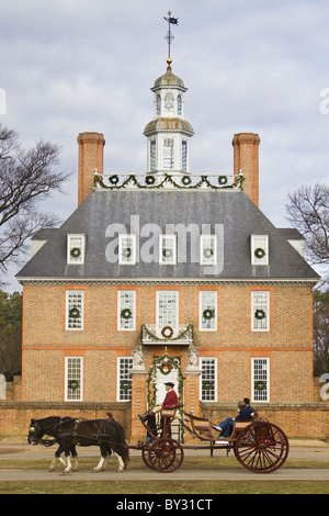 Kutscher und Touristen fahren durch den Gouverneurspalast, geschmückt mit Weihnachtsschmuck in historischen Colonial Williamsburg, VA. Stockfoto