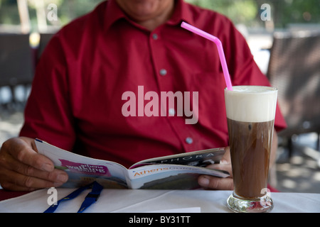 Der Senior Athen Reiseführer in einem Café im Schatten lesen. Stockfoto