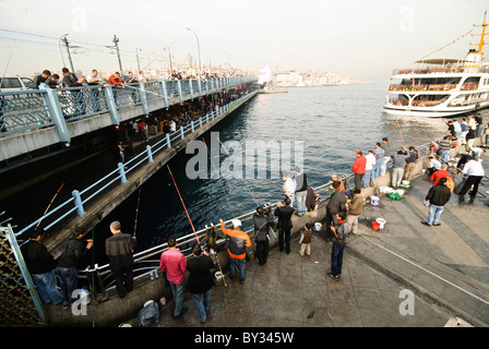 ISTANBUL, Türkei – lokale Fischer säumen das Geländer der historischen Galata-Brücke, die das Goldene Horn überspannt. Die Brücke, die Eminonu mit Karakoy verbindet, ist seit Generationen ein beliebter Angelplatz. Dutzende Angler versammeln sich routinemäßig entlang der oberen Ebene der Brücke, um ihre Linien in die Gewässer unter ihnen zu werfen. Stockfoto