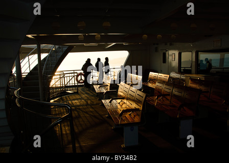 ISTANBUL, Türkei / Türkiye / Türkiye — die untergehende Sonne zeigt sich auf dem Deck einer Passagierfähre auf dem Bosporus von Istanbul. Der Bosporus, ein wichtiger Wasserweg, der das Schwarze Meer mit dem Marmarameer verbindet, bietet atemberaubende Szenen von Istanbul mit seinen historischen Wahrzeichen und der geschäftigen maritimen Aktivität. Diese ikonische Meerenge teilt die Stadt in europäische und asiatische Seiten mit wunderschönen Palästen, Moscheen und Brücken am Wasser. Stockfoto