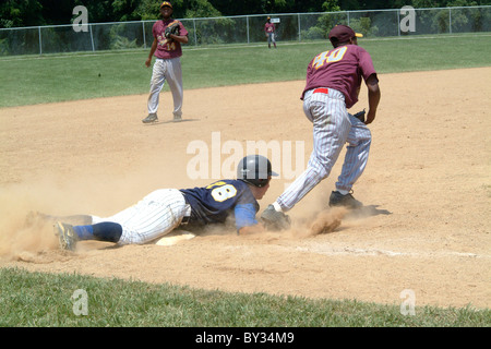 Spieler rutscht und ist sicher auf Basis in einer High School Baseball-Spiel Stockfoto