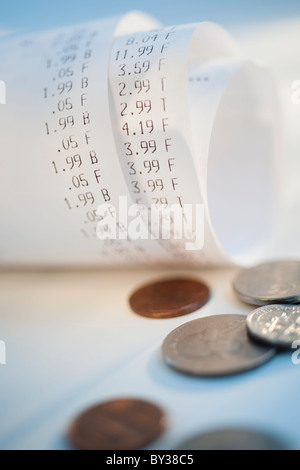 Münzen von aufgerollt Quittungen mit Preisen Stockfoto