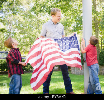 USA, New York, Flandern, Vater mit zwei jungen (4-5, 8-9) hängende amerikanische Flagge am Mast Stockfoto