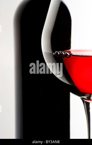 Stilleben mit Flasche und Glas Rotwein auf weißem Hintergrund. Stockfoto