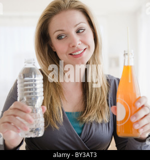 USA, New Jersey, Jersey City, junge Frau, die versucht, die Wahl zwischen Bio-Säfte und Mineralwasser Stockfoto