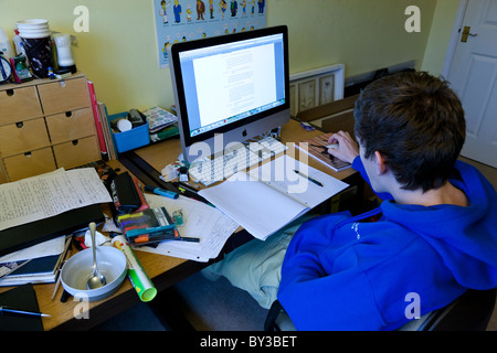 Schüler arbeiten in seinem Schlafzimmer mit einen unordentlichen Schreibtisch und einen Imac. Stockfoto