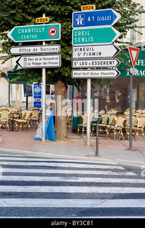 Verkehrszeichen vor einem Café auf der Hauptstraße durch die Stadt von Chantilly in Frankreich Stockfoto