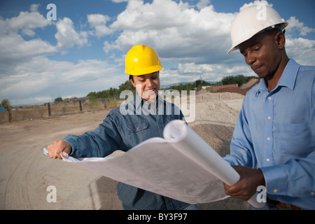 Zwei Bauarbeiter diskutieren Baupläne auf der Baustelle Stockfoto