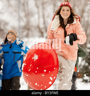 USA, Utah, Provo, Teenage (16-17) Mädchen laufen mit Schlitten, jungen und Mädchen (10-11, 12-13) im Hintergrund Stockfoto