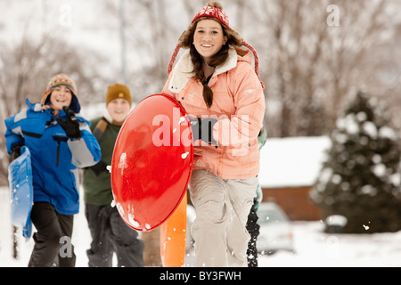 USA, Utah, Provo, Teenage (16-17) Mädchen laufen mit Schlitten, jungen und Mädchen (10-11, 12-13) im Hintergrund Stockfoto