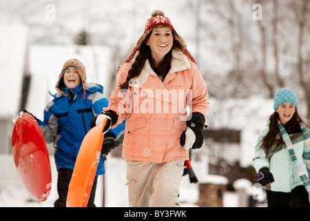 USA, Utah, Provo, Teenage (16-17) Mädchen laufen mit Schlitten, jungen und Mädchen (10-11, 12-13) im Hintergrund Stockfoto