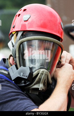 Ein Feuerwehrmann auf einer Atmung-Apparat-Getriebe für einen Schutzanzug an eine chemische Haz Mat Spill Vorfall setzen Stockfoto