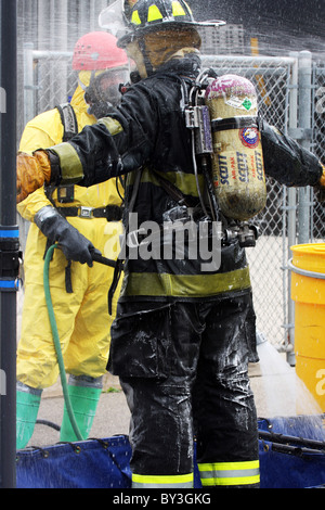 Ein Feuerwehrmann immer unten nach einem chemischen Haz Mat Spill Vorfall geschrubbt Stockfoto