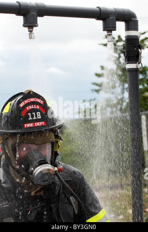 Ein Feuerwehrmann immer unten nach einem chemischen Haz Mat Spill Vorfall gesprüht Stockfoto