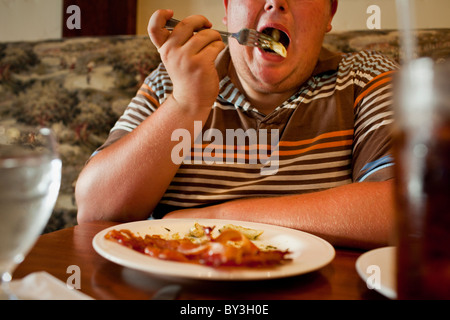 La Grange, California, Vereinigte Staaten von Amerika.  Ein Teenager nimmt einen Bissen von Nudeln zum Mittagessen, mit einer Seitenlänge von Speck. Stockfoto