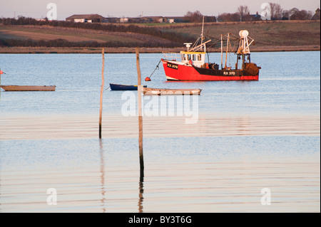 roten Fischerboot vor Anker unter Ruderboote vor der Isle of Sheppey Stockfoto