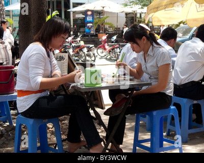 Vietnamesen und Touristen sitzen an Tischen und Essen im Freien Straße Stände von Imbissstände in Ho-Chi-Minh-Stadt (Saigon) Stockfoto