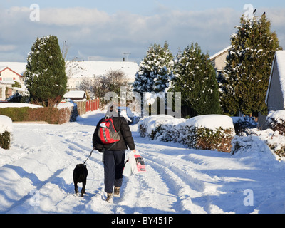 Mensch und Hund zu Fuß durch den Schnee entlang einem Vorort Straße im Winter 2010. UK-Großbritannien Stockfoto