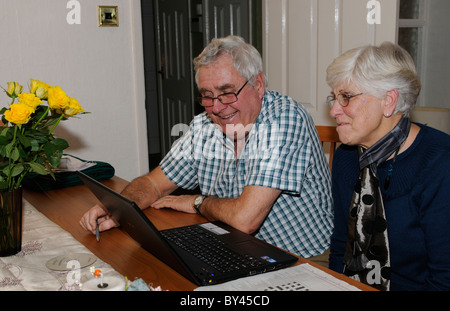 Älteres Ehepaar ihren Laptop benutzen Skype Freunde über das Internet aus ihrer Heimat Stockfoto