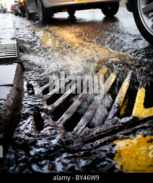 Regenwasser fließt ein Gitter an der Seite einer Straße in Birmingham, UK Stockfoto