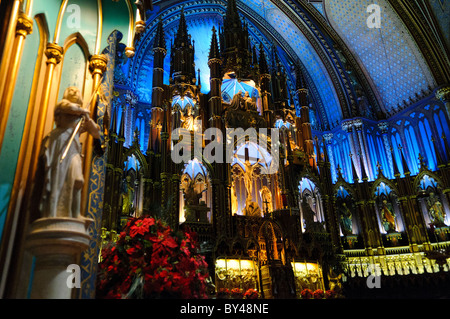 MONTREAL, Kanada – der Hauptaltar und das Heiligtum der Basilika Notre-Dame zeigt außergewöhnliche, im gotischen Stil gefertigte Handwerkskunst mit seinem aufwendig geschnitzten Lindenholzaltar und der dramatischen blauen Gewölbedecke, die mit goldenen Sternen verziert ist. Das Heiligtum wurde in den 1870er Jahren von Victor Bourgeau neu gestaltet und bietet eine reiche Farbpalette aus Blau, Azures, Rot, Violett, Silber, und Gold. Dieses Meisterwerk religiöser Architektur gehört zu den beeindruckendsten Kircheneinrichtungen Nordamerikas. Stockfoto