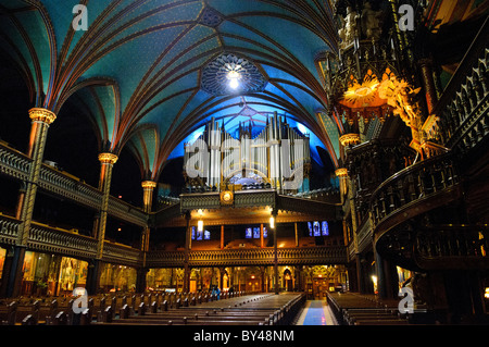 MONTREAL, Kanada — wenn man auf den Eingang der Basilika Notre-Dame blickt, zeigt sich die monumentale Pfeifenorgel Casavant Frères, die 1891 mit 9.000 Pfeifen und vier Tastaturen installiert wurde. Die Basilika war nach ihrer Fertigstellung in den 1840er Jahren die größte Kirche Nordamerikas. Das Innere der Basilika besticht durch außergewöhnliche, im gotischen Stil erbaute Architektur und dramatische Beleuchtung. Dieser Blick vom Heiligtum hebt die Pracht des Hauptschiffs der historischen Kirche hervor. Stockfoto