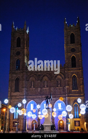 MONTREAL, Kanada – während der Wintersaison erleuchten die Lichter des Platzes Place d'Armes vor der historischen Basilika Notre-Dame. Der historische Platz aus der Kolonialzeit von Montreal bildet einen dramatischen Vorsprung zur neugotischen Basilika. Diese festliche Ausstellung im historischen Viertel von Old Montreal schafft eine der meistfotografierten Winterszenen der Stadt. Stockfoto