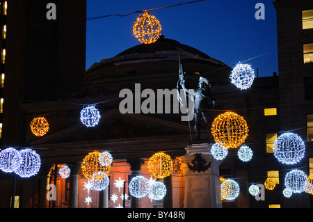 MONTREAL, Kanada – während der Wintersaison erleuchten die Lichter des Platzes Place d'Armes vor der historischen Basilika Notre-Dame. Der historische Platz aus der Kolonialzeit von Montreal bildet einen dramatischen Vorsprung zur neugotischen Basilika. Diese festliche Ausstellung im historischen Viertel von Old Montreal schafft eine der meistfotografierten Winterszenen der Stadt. Stockfoto