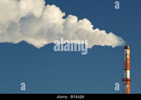 Rauch, Gas und Dampf Wogen aus einem Schornstein vor blauem Himmel. Stockfoto