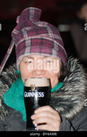 Eine asiatische Frau Getränke ein Pint Guinness in einem irischen Pub in Limerick, Republik von Irland Stockfoto