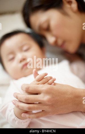 Mutter und Baby Boy Holding Hands im Schlaf Stockfoto