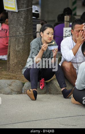 junge Japanerin mit Tabi Schuhen Essen an Sanja Matsuri, Asakusa, Tokio, Japan Stockfoto