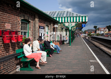 Menschen sitzen auf Bänken an Sheringham Train Station Norfolk East Anglia in England Stockfoto