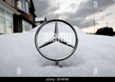 Ein Mercedes-Motorhaube / Hood Star wird fotografiert auf einen schneebedeckten Mercedes Auto nach Schneestürme Großbritannien getroffen. Stockfoto