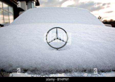 Ein Mercedes-Motorhaube / Hood Star wird fotografiert auf einen schneebedeckten Mercedes Auto nach Schneestürme Großbritannien getroffen. Stockfoto