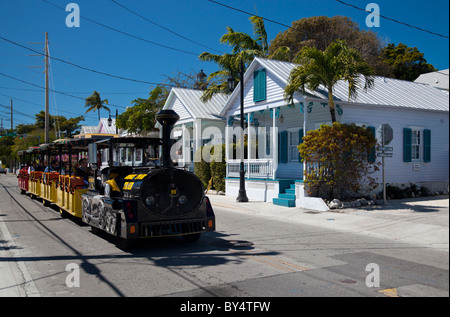 Der Conch Tour Zug geht eine Reihe von hübschen kleinen Hütte Stil Häuser in Key West, Florida, USA Stockfoto