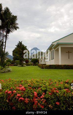 Die Parroquia San Juan Bosco Kirche in La Fortuna de San Carlos mit dem Arenal Vulkan droht in den Hintergrund, Costa Rica. Stockfoto