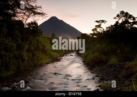 Sonnenaufgang am Fluss Tabacon und aktivste Vulkan Costa Ricas der Vulkan Arenal in Arenal Nationalpark, Alajuela, Costa Rica. Stockfoto