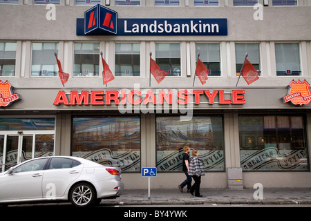 Menschen zu Fuß vorbei an Hauptsitz der Bank "Landsbanki Islands" und "American Style" Hamburger Restaurant. Stockfoto