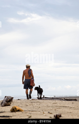 Mann geht mit seinem Hund am Strand in den frühen Morgenstunden in Puerto Viejo de Talamanca, Provinz Limon, Costa Rica. Stockfoto