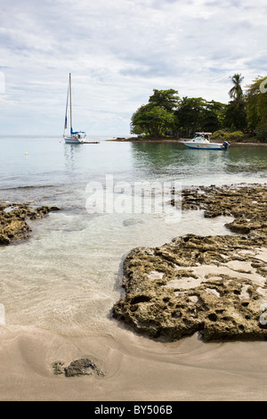 Segelboot und Motorboot vertäut am palmengesäumten Strand in Puerto Viejo de Talamanca, Provinz Limon, Costa Rica. Stockfoto