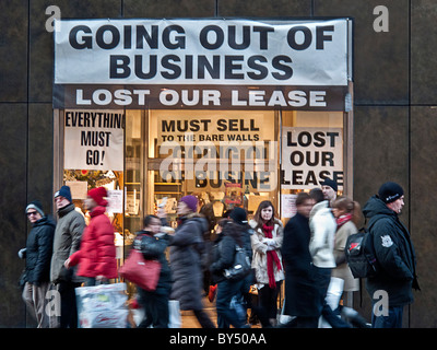 Winter angezogen Fußgänger zu Fuß vorbei an einem Store bietet ein Going Out of Business-Verkauf auf der Fifth Avenue in Manhattan, New York City. Stockfoto